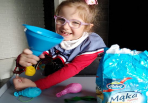 dziewczynka w okularach wsypuje mąkę przez lejek do balonów